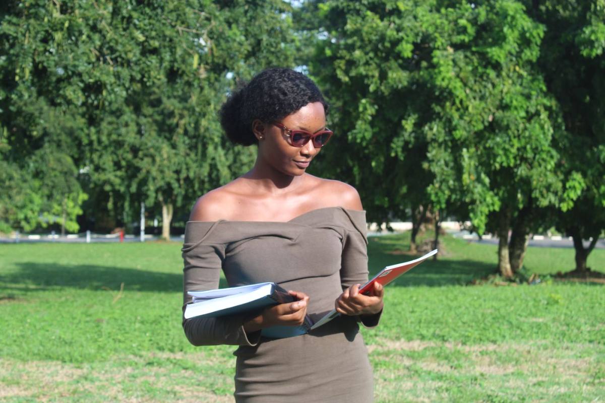 Une jeune femme, ses cahiers sous le bras, sortant de cours